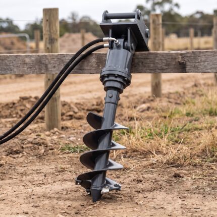 Auger drive and 12 inch bit laid out full length on the soil showing the flighting