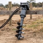 Hydraulic auger drive with a 12 inch spiral bit standing upright at a fencing site