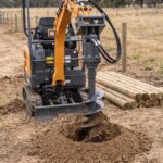 Auger drive mounted on a mini excavator boring a fence post hole
