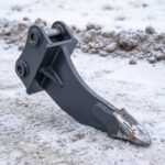 Single-shank frost ripper attachment resting on frozen packed ground