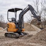 MX-17 mini excavator lifting a full bucket of gravel from a stockpile