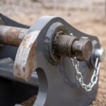 Macro detail of the quick coupler locking wedge, threaded adjuster and safety pin